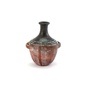 May include: A small, brown clay vase with white geometric designs. The vase has two small handles on the sides and a narrow neck.