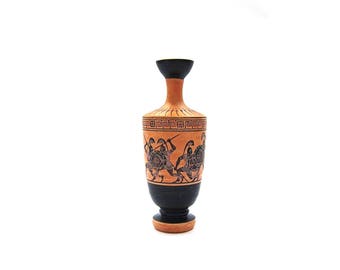 May include: A small, brown ceramic vase with a black top and a black and white design of Greek warriors. The vase has a geometric pattern around the top.
