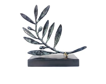 May include: A bronze olive branch sculpture on a black marble base. The branch is stylized and has several leaves and olives.