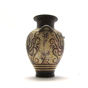 May include: A small, brown ceramic vase with a white and brown geometric design. The vase has a round body and a narrow neck.