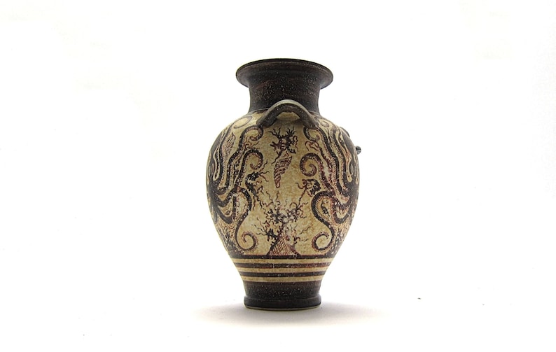 May include: A small, brown ceramic vase with a white and brown geometric design. The vase has a round body and a narrow neck.