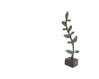 May include: A green metal sculpture of a leafy branch on a black base. The sculpture is a decorative piece for a home or office.