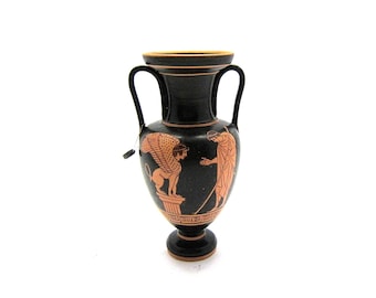 May include: Black and orange ceramic amphora vase with a winged creature and a figure in a robe painted on the side.