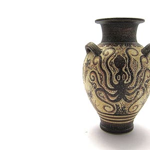 May include: A ceramic amphora vase with a black and white design of an octopus. The vase has two handles and a narrow neck.