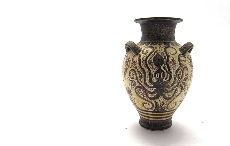 May include: A ceramic amphora vase with a black and white design of an octopus. The vase has two handles and a narrow neck.