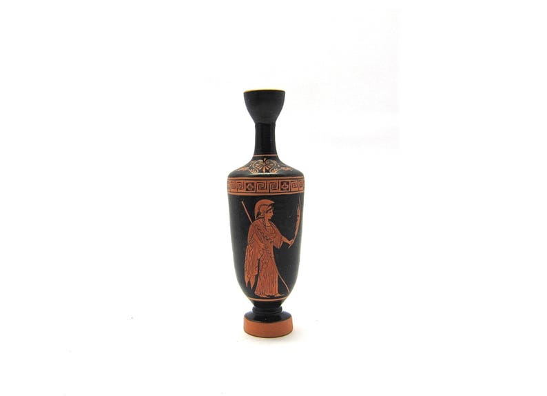 Puede incluir: Jarr&oacute;n de cer&aacute;mica negro y rojo con un dise&ntilde;o griego que representa una figura sosteniendo una lanza. El jarr&oacute;n tiene un cuello estrecho y una base redonda.