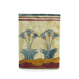 May include: A vintage tile with a painted design of blue and yellow flowers on a cream background. The tile has a red, white, and blue border.