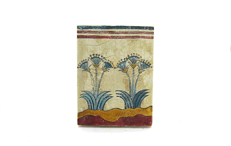May include: A vintage tile with a painted design of blue and yellow flowers on a cream background. The tile has a red, white, and blue border.
