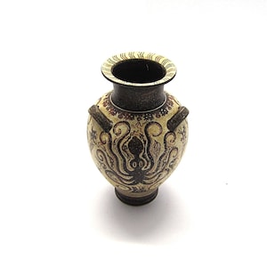 May include: A small, ceramic vase with a brown and white design featuring an octopus. The vase has two handles and a round body.
