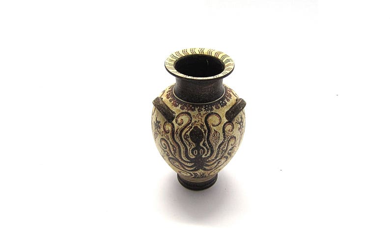May include: A small, ceramic vase with a brown and white design featuring an octopus. The vase has two handles and a round body.
