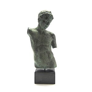 Pu&ograve; includere: Una scultura in bronzo di un torso maschile su una base nera. La scultura &egrave; una replica di una statua greca classica.