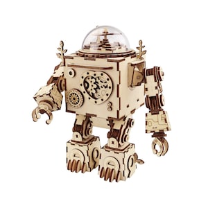 Può includere: Un robot di legno a forma di carillon con una cupola trasparente in cima. Il robot ha un design a forma di cuore sul petto e ingranaggi su braccia e gambe. Il robot è in piedi su uno sfondo bianco.