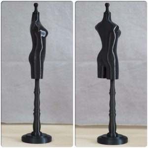 May include: A black plastic dress form with a stand. The dress form is a simple design with a rounded bust and a flat base. The stand is a simple design with a round base and a tall, slender column.