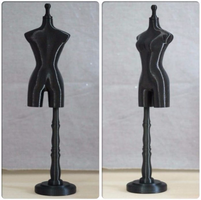 May include: A black plastic dress form on a stand. The dress form is a small size and has a simple design.