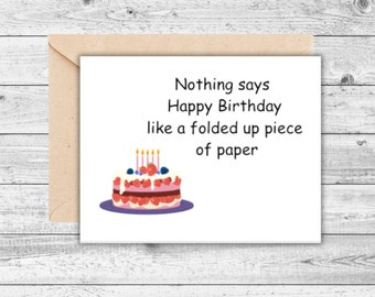 May include: A birthday greeting card with a tan envelope. The white card has the text "Nothing says Happy Birthday like a folded up piece of paper" and a cake illustration with candles and berries.