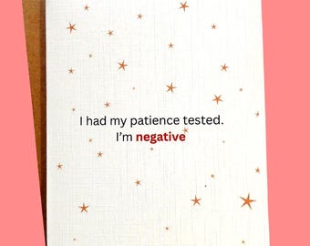 May include: A white greeting card with a textured surface and gold star illustrations. The card reads, "I had my patience tested. I'm negative" in black and red text. The card is inside a brown envelope.