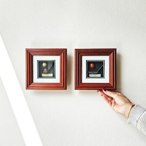 May include: Two framed pictures with a golf theme. The frames are dark wood with a gold trim. The pictures are of a golf club and a golf ball.