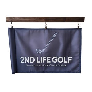 May include: A navy blue golf sign with the text "2ND LIFE GOLF" and a golf club graphic. The sign is suspended from a dark brown wooden bar with metal clips. The text "GIVING OLD CLUBS A SECOND CHANCE" is below the main text.