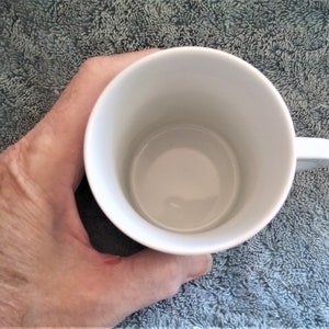 K&ouml;nnte beinhalten: Eine wei&szlig;e Keramiktasse mit Henkel. Die Tasse ist leer.