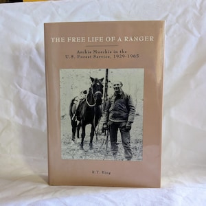May include: A hardcover book titled "THE FREE LIFE OF A RANGER" with a sepia-toned image of a man and a horse. The book's subtitle reads "Archie Murchie in the U.S. Forest Service, 1929-1965." The author's name, R.T. King, is at the bottom.