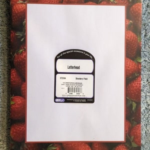 May include: Letterhead stationery with a strawberry design. The border features a pattern of ripe red strawberries. The center has a white space for writing, with the words "Letterhead" and "Strawberry Patch" printed on the packaging.