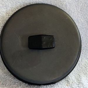 May include: Black round lid with a black rectangular handle.