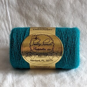 May include: A teal spool of embroidery floss with a gold label that reads "Pretty Punch Shoppettes, Inc. 1981 10th Anniversary 1991 Sanford, FL 32771 -Washable -Dryable"