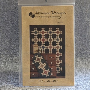 May include: A brown paper pattern envelope with a quilt design on the front. The pattern is called "Tic-Tac-Mo" and is from Atkinson Designs, "one of life's simple pleasures". The pattern number is SPL-121.