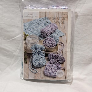 May include: A Fresh Start Spa Set crochet kit. The kit includes crocheted spa accessories in shades of blue and purple. Items include washcloths, soap savers, and a bath pouf. The kit is packaged in a clear plastic bag.