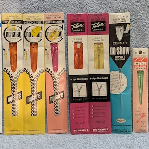May include: Assortment of zipper packages in various colors and sizes. The packages feature different brands, including Conmar, Talon, and Nylaire. The zippers are for use in clothing and other sewing projects.