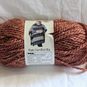 May include: A skein of brown and white yarn with a label that reads "Charisma Knit Poncho, 93 yds/3 oz. 85 m/85 g".