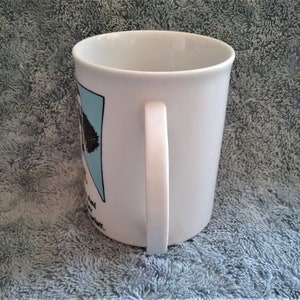 K&ouml;nnte beinhalten: Wei&szlig;e Keramiktasse mit einer schwarz-wei&szlig;en Cartoon-Illustration eines Hundes mit Hut und Sonnenbrille. Der Text "Ich bin kein Hunde-Mensch, ich bin ein Hunde-Besessener" ist auf die Tasse gedruckt.