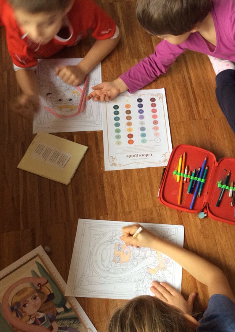 May include: Three children are coloring in a room with wooden floors. They are using colored pencils and a color guide. The color guide has 36 different colors. The children are coloring in a variety of images, including a girl with a crown, a girl with a flamingo, and a girl with a flower.