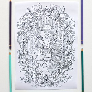 May include: A black and white line drawing of a girl with long hair holding a dog. The girl is wearing a dress and a bow. The drawing is surrounded by intricate floral designs.