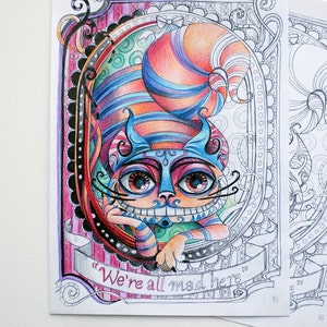 May include: A colorful illustration of the Cheshire Cat from Alice in Wonderland. The cat is smiling with a wide grin and has a blue and orange striped hat. The text "We're all mad here" is written on a banner below the cat.