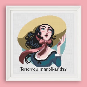 Könnte beinhalten: Kreuzstichmuster mit einer Frau mit langen dunklen Haaren, die einen großen Strohhut und einen rosafarbenen Schal trägt. Der Text "Tomorrow is another day" befindet sich unter der Frau.