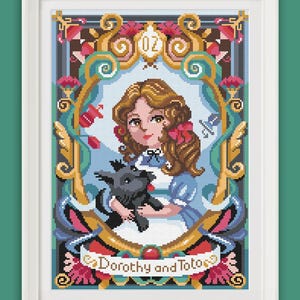 May include: A cross-stitch pattern featuring Dorothy from The Wizard of Oz, holding her dog Toto. The pattern is framed in a gold and blue frame with floral accents. The text "Dorothy and Toto" is written below the image.