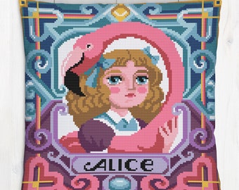 Puede incluir: Una almohada bordada en rosa y azul con una niña sosteniendo un flamenco. La almohada tiene un marco decorativo y la palabra "Alice" escrita en ella.