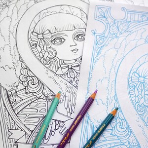 May include: Two coloring book pages with intricate line drawings of a girl with wings and a floral design. Three colored pencils are laying on top of the pages, one teal, one purple, and one blue.