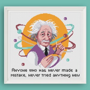 May include: Cross-stitch portrait of Albert Einstein in a white frame. The image features Einstein with white hair, a purple vest, and a black tie, set against an orange background with colorful atom-like shapes. The quote reads: "Anyone who has never made a mistake, never tried anything new."