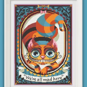 May include: A colorful cross-stitch pattern of the Cheshire Cat from Alice in Wonderland. The cat is wearing a hat and has a wide grin. The text "We're all mad here" is written on a banner below the cat.