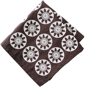 May include: A brown fabric napkin with a white floral pattern. The flowers are stylized and have a circular shape.
