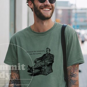 May include: A moss green t-shirt with a graphic of a man in a chair and the text "built for pleasure, not for speed." The shirt also has the text "Dammit Judy" in a circle.