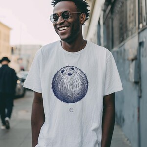 May include: A white t-shirt with a blue drawing of a bowling ball. The shirt has a crew neck and short sleeves. The person wearing the shirt is smiling and wearing round sunglasses.