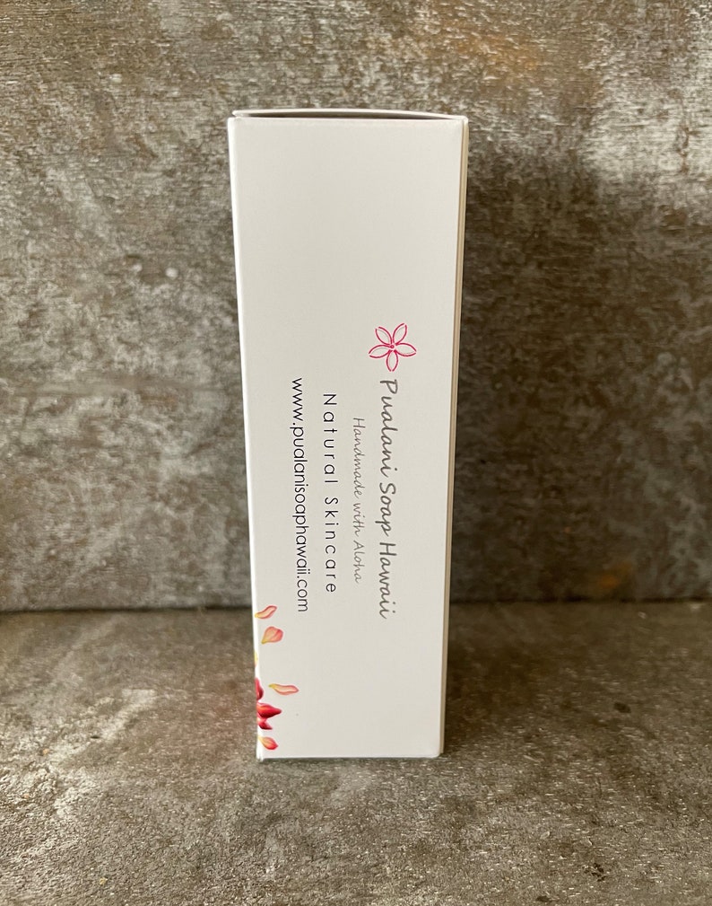 May include: A white rectangular box with the text "Pualani Soap Hawaii" and "Natural Skincare" in black. A pink flower graphic and red petal design are also visible. The website address is www.pualanisoaphawaii.com.