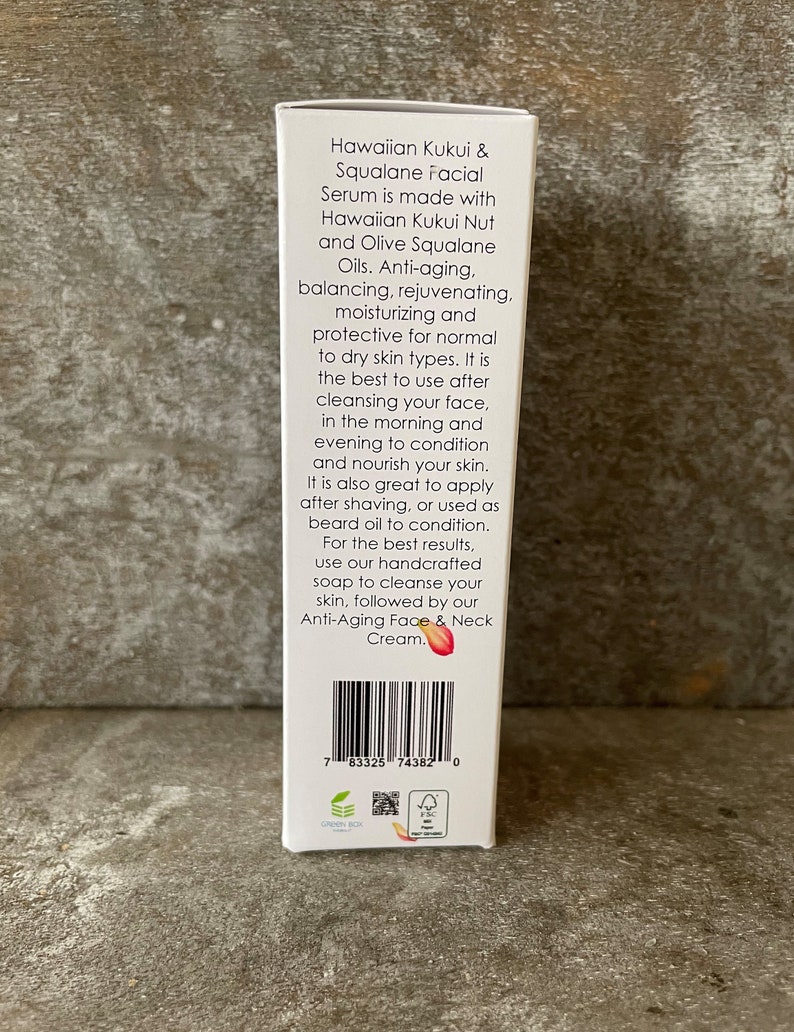 May include: A white box of Hawaiian Kukui & Squalane facial serum. The text on the box describes the product's ingredients and benefits, including anti-aging and moisturizing properties. The box also includes a barcode and other product information.