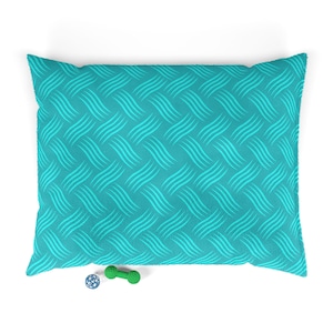 May include: A turquoise blue dog bed with a wavy pattern. The bed is filled with a soft, comfortable material. A green bone-shaped toy and a blue ball are in front of the bed.