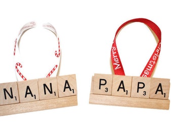May include: Two wooden Christmas ornaments. One says "NANA" with a candy cane ribbon. The other says "PAPA" with a red ribbon that says "Merry Christmas". Both are on a white background.