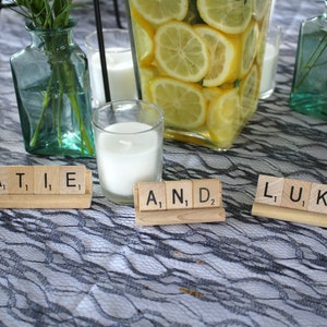 May include: A table setting with three place cards made from wooden scrabble tiles. The tiles spell out the names "KATIE", "AND", and "LUKE".