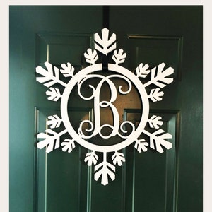 May include: White snowflake-shaped door hanger with a circle in the center featuring the letter "B" in a cursive font.